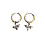 Boucles d’oreilles créoles dorées en acier inoxydable avec pendentif libellule et oxyde de zirconium sur fond blanc