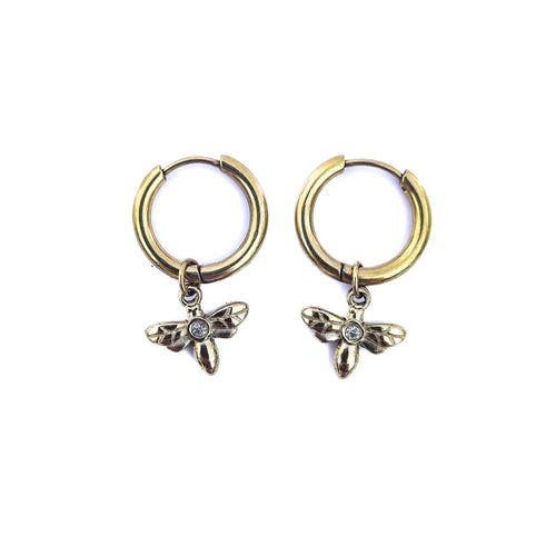 Boucles d’oreilles créoles dorées en acier inoxydable avec pendentif libellule et oxyde de zirconium sur fond blanc