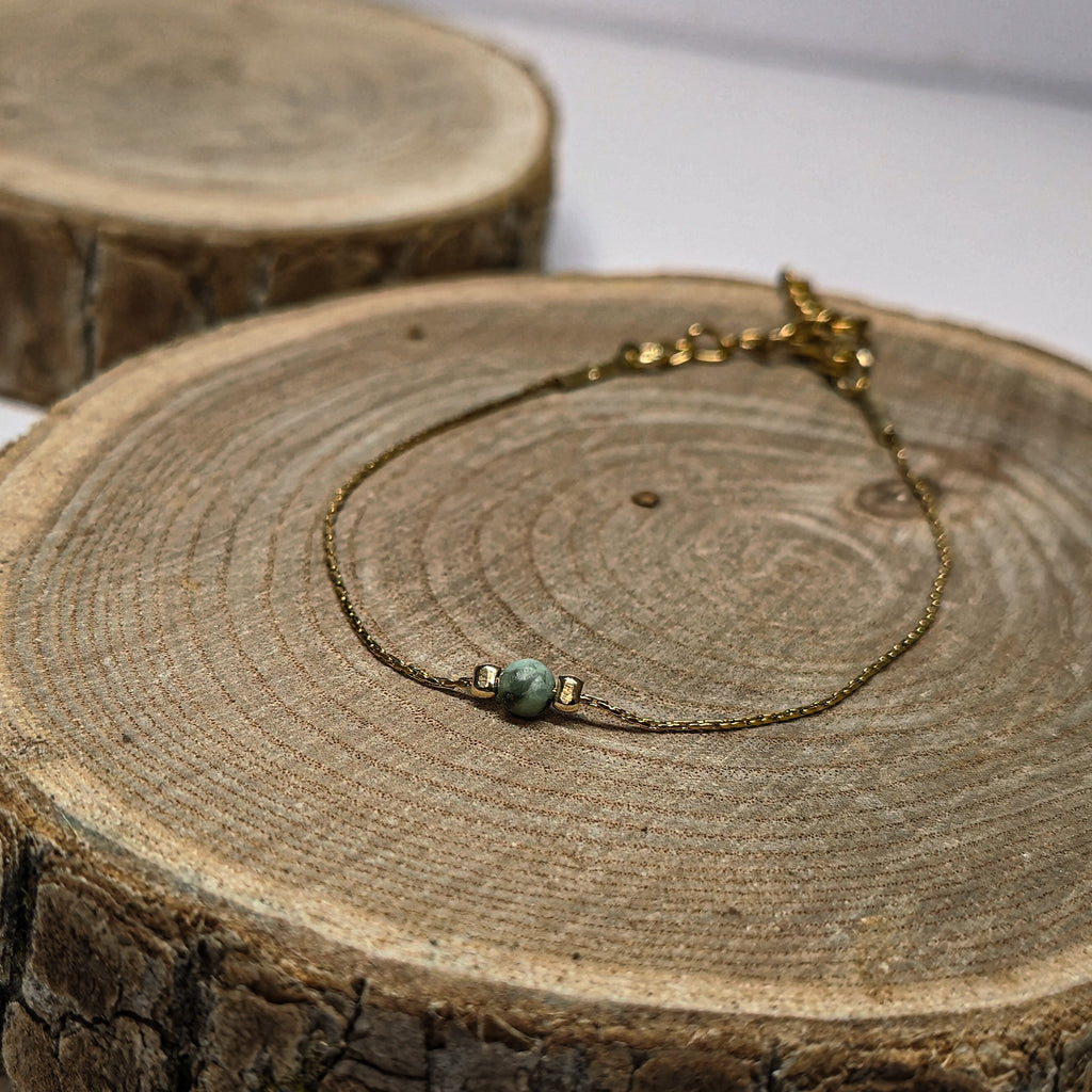 Bracelet doré minimaliste en acier inoxydable orné d’une perle de jaspe africaine, création raffinée Clyvia Bijoux.