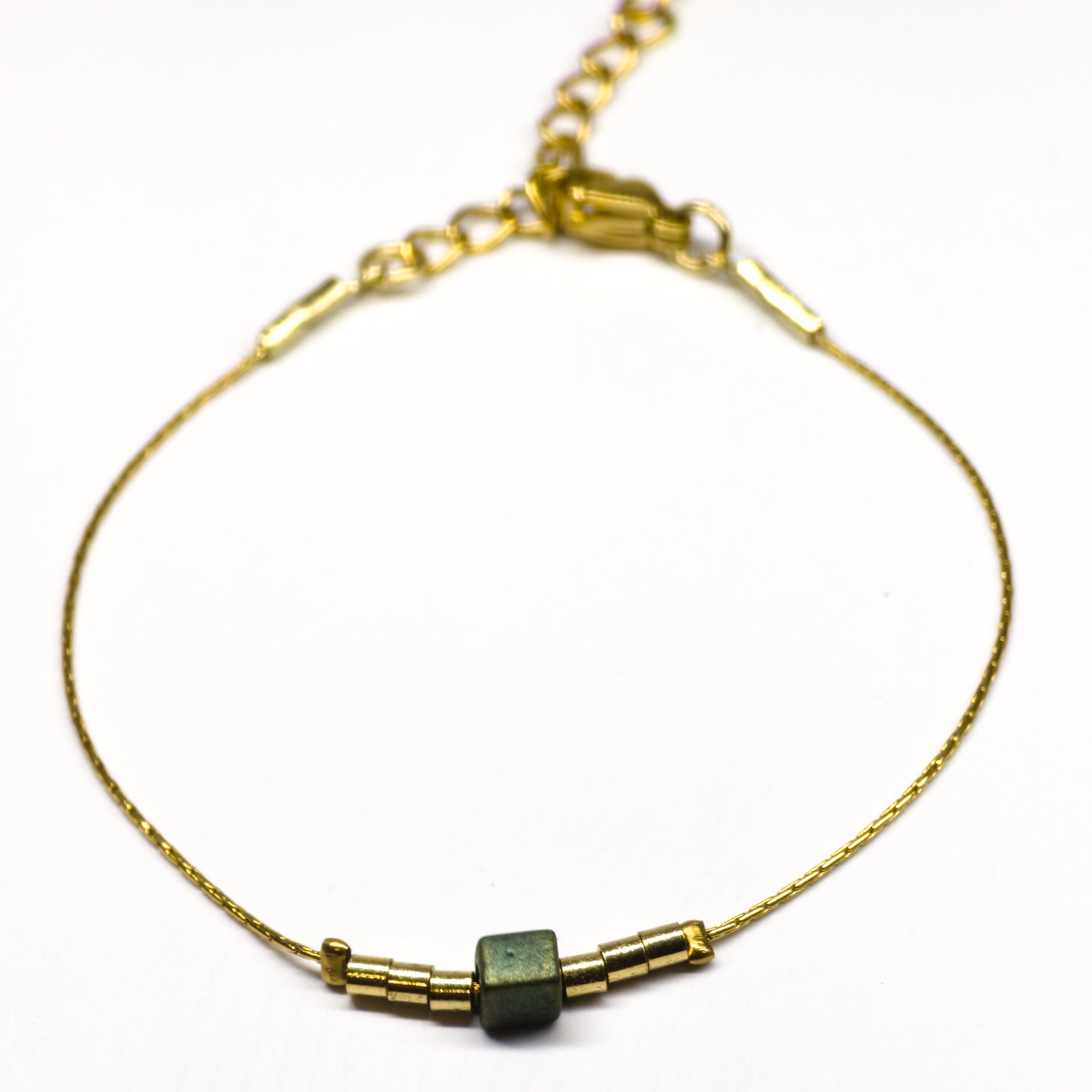 Bracelet doré en acier inoxydable orné d’une perle en verre irisée bleu-vert, bijou minimaliste et élégant signé Clyvia Bijoux.