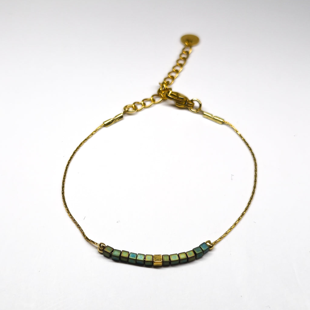 Bracelet fin doré en acier inoxydable orné de perles en verre irisées vert-bleu, bijou élégant et lumineux signé Clyvia Bijoux.