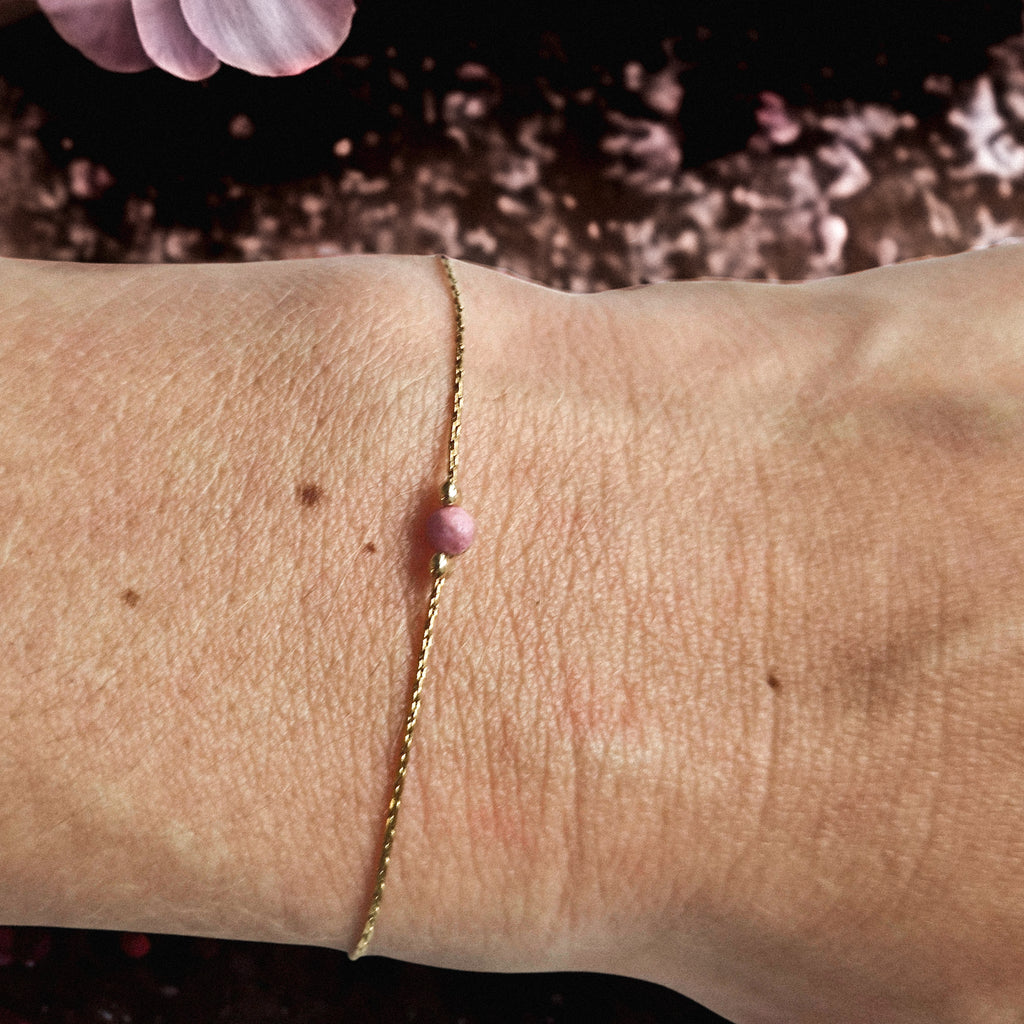 Bracelet fin doré en acier inoxydable avec pierre naturelle de rhodonite, bijou délicat porté au poignet, création Clyvia Bijoux.