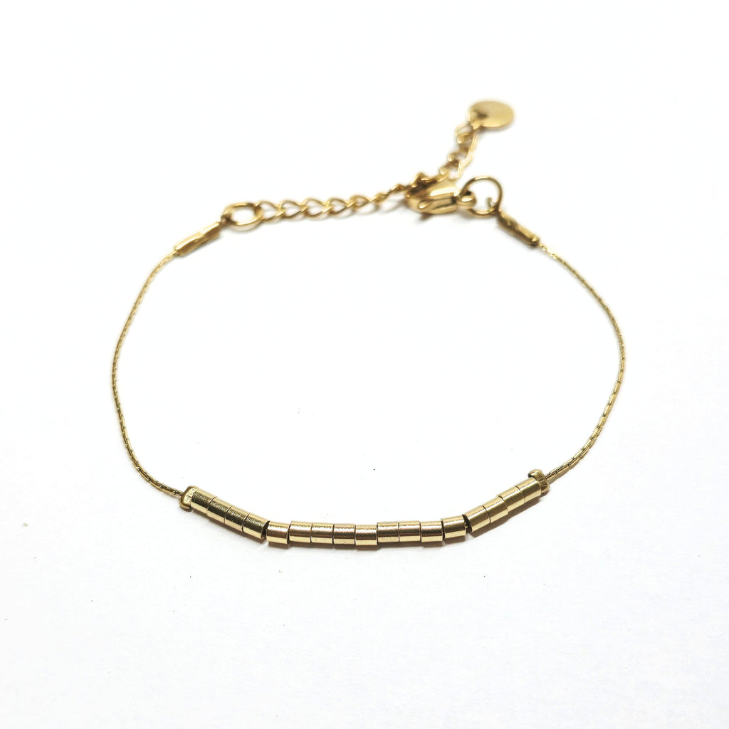 Bracelet fin doré en acier inoxydable orné de petites perles tubes dorées, bijou minimaliste et élégant signé Clyvia Bijoux.