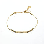 Bracelet fin doré en acier inoxydable orné de petites perles tubes dorées, bijou minimaliste et élégant signé Clyvia Bijoux.