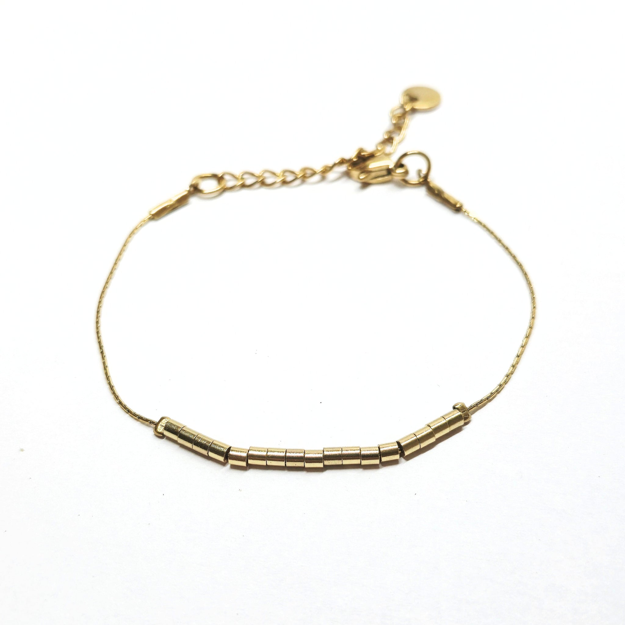 Bracelet fin doré en acier inoxydable orné de petites perles tubes dorées, bijou minimaliste et élégant signé Clyvia Bijoux.