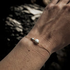 Bracelet fin doré orné de pierres naturelles de howlite blanche porté au poignet, bijou élégant et intemporel Clyvia Bijoux.