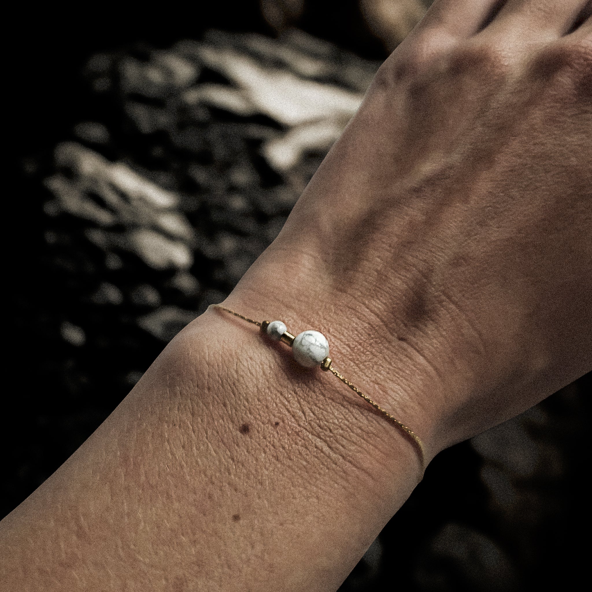 Bracelet fin doré orné de pierres naturelles de howlite blanche porté au poignet, bijou élégant et intemporel Clyvia Bijoux.