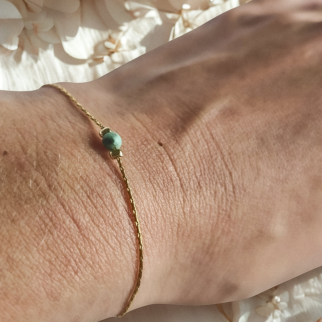 Bracelet fin doré avec perle de jaspe africaine porté au poignet, bijou délicat et lumineux Clyvia Bijoux.