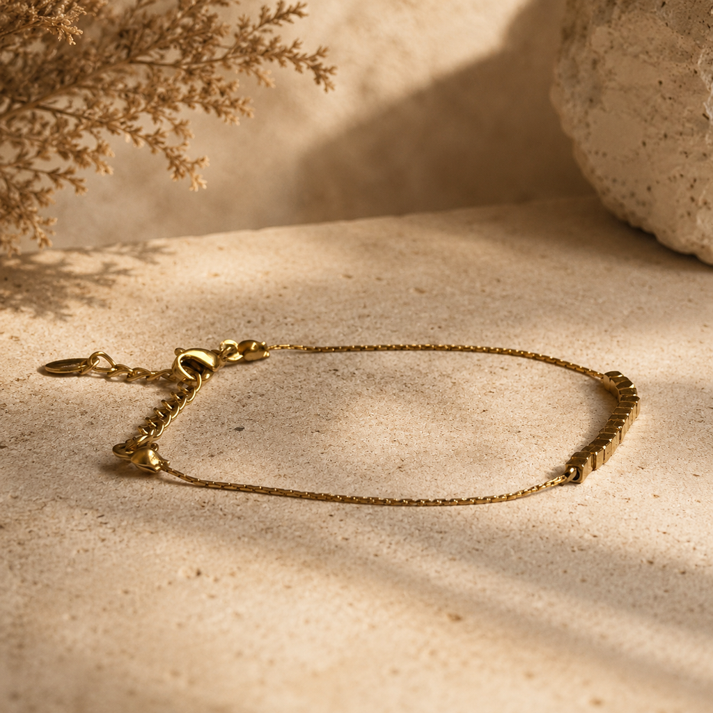 Bracelet doré fin avec perles carrées et fermoir réglable sur fond pierre