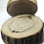 Bracelet fin doré en acier inoxydable avec perles de howlite blanche posé sur fond bois, bijou délicat et apaisant signé Clyvia Bijoux.