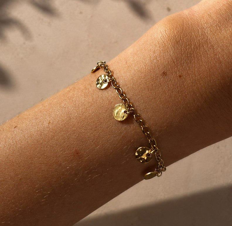 Bracelet doré à médailles martelées porté au poignet