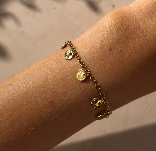 Bracelet doré à médailles martelées porté au poignet