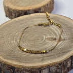 Bracelet fin en acier inoxydable doré et petites perles sur support bois - Clyvia Bijoux 