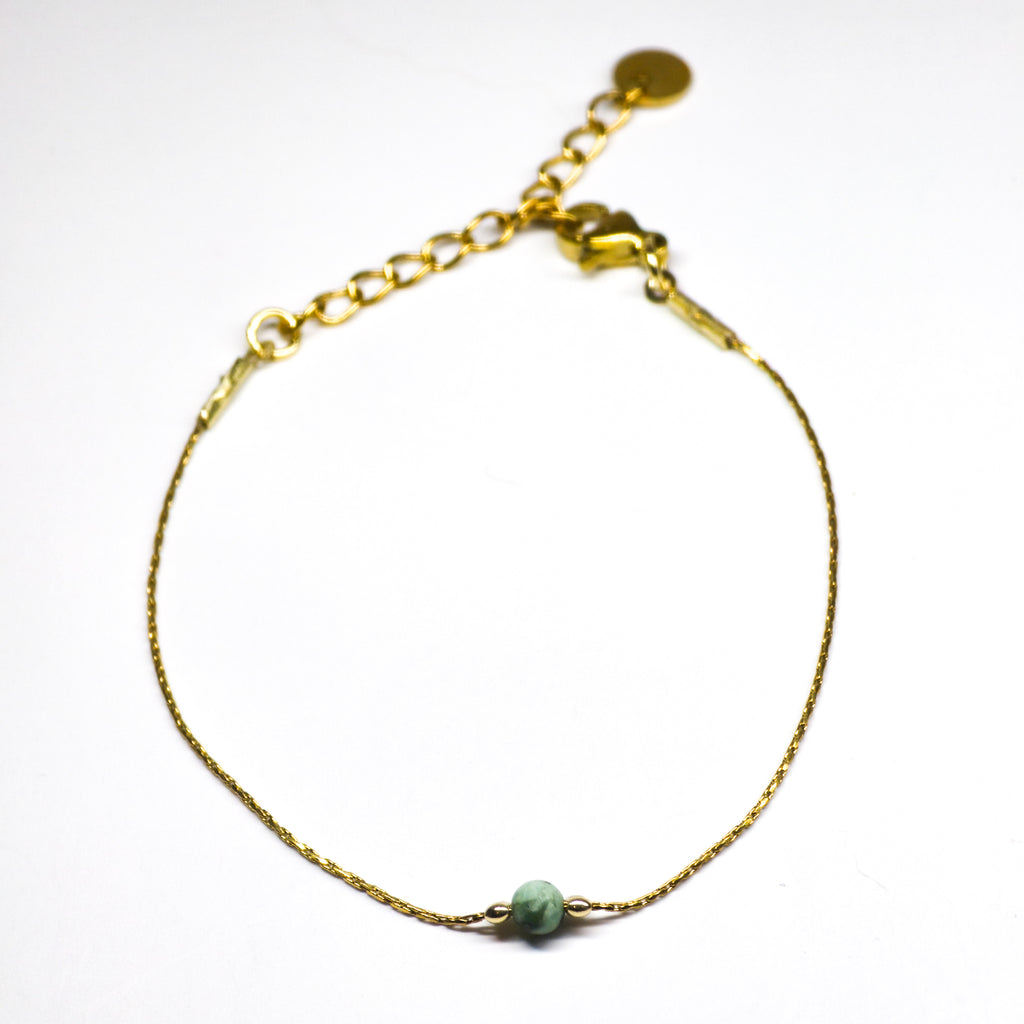 Bracelet fin doré en acier inoxydable avec une perle centrale de jaspe africaine, bijou élégant et naturel signé Clyvia Bijoux.