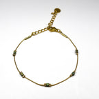 Bracelet fin doré en acier inoxydable avec petites perles irisées vert-bleu, bijou délicat et lumineux signé Clyvia Bijoux.