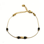 Bracelet fin doré en acier inoxydable décoré de perles noires et dorées, bijou minimaliste et chic signé Clyvia Bijoux.