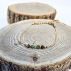 Bracelet doré en acier inoxydable avec jaspe bleu-vert présenté sur support en bois