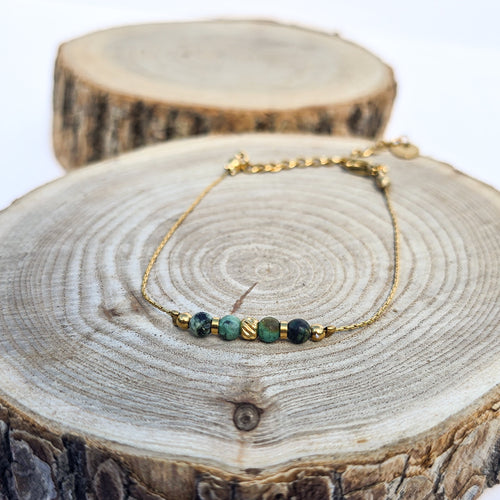 Bracelet doré en acier inoxydable avec jaspe bleu-vert présenté sur support en bois