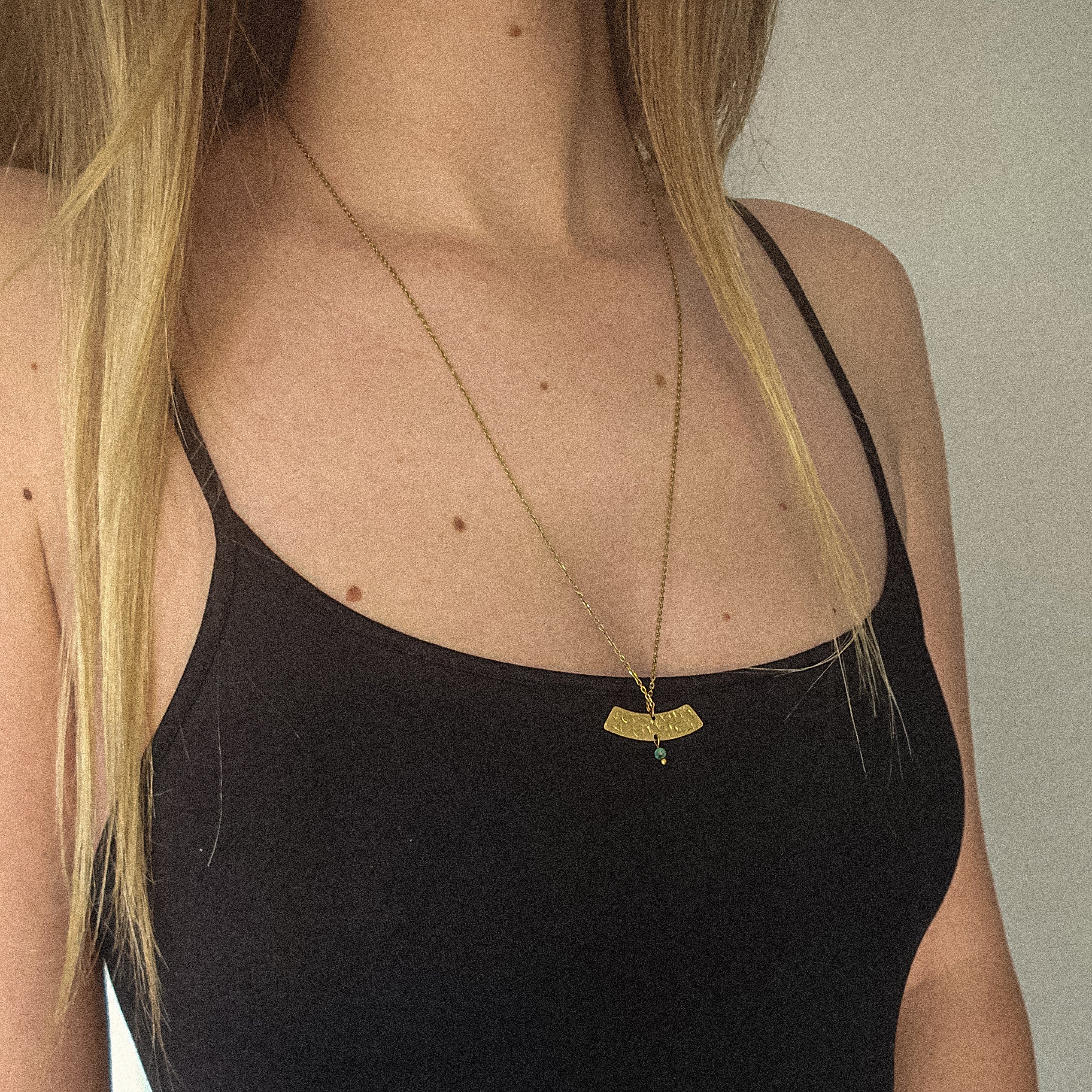 Collier en acier inoxydable doré porté, avec pendentif texturé et petite perle de turquoise africaine