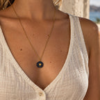 Collier long doré avec pendentif soleil en lapis-lazuli porté par une femme