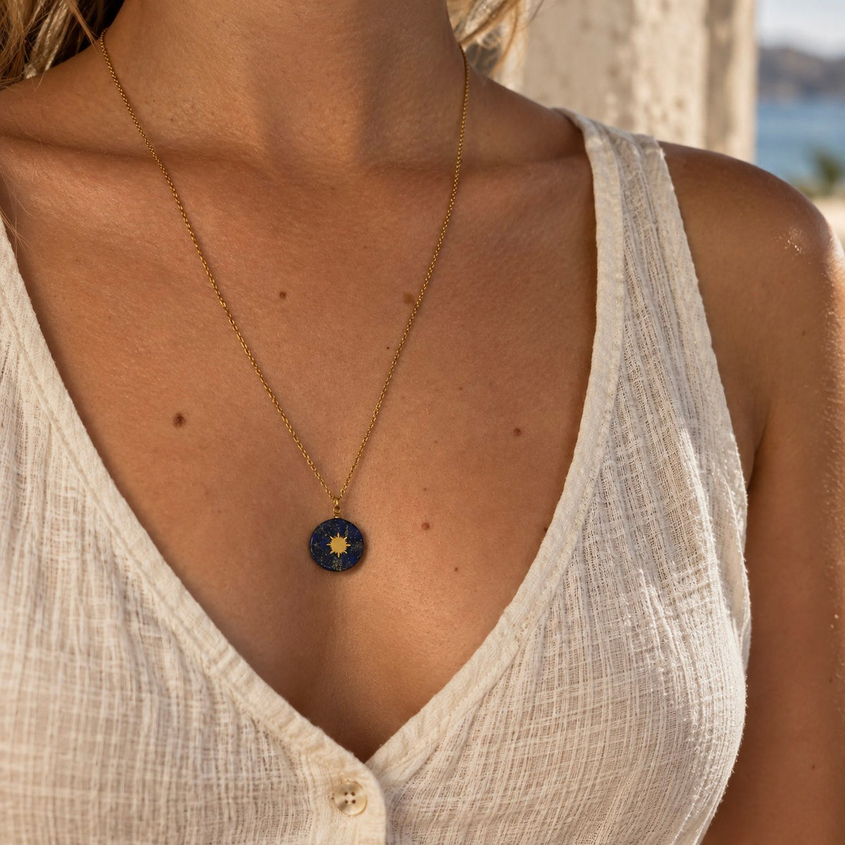 Collier long doré avec pendentif soleil en lapis-lazuli porté par une femme