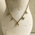 Collier doré à breloques en acier inoxydable sur présentoir avec lune, œil, étoile, libellule et demi-corne