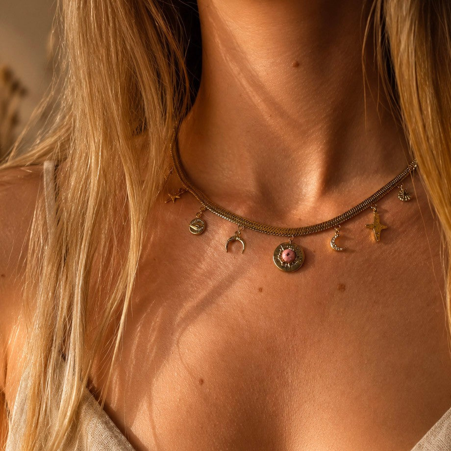 Collier doré femme porté au cou avec chaîne plate et breloques étoile, lune, oeil et pierre rose