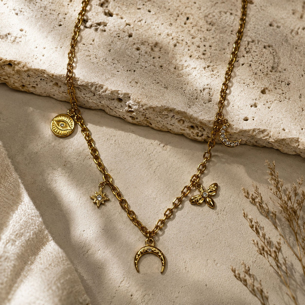 Collier doré à breloques lune, oeil, étoile et fleur sur fond pierre
