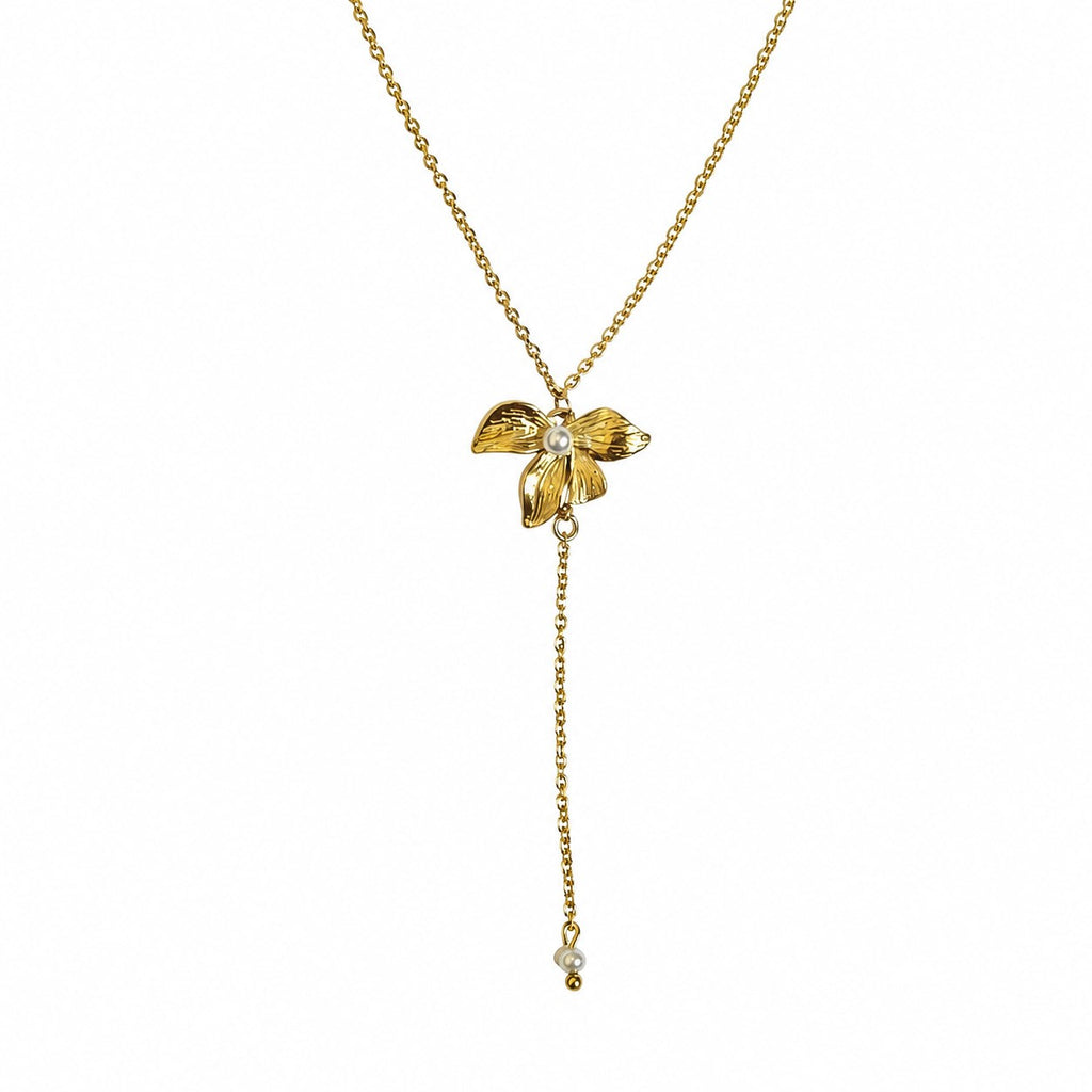 Collier doré femme avec pendentif fleur, perle blanche et chaîne pendante sur fond blanc
