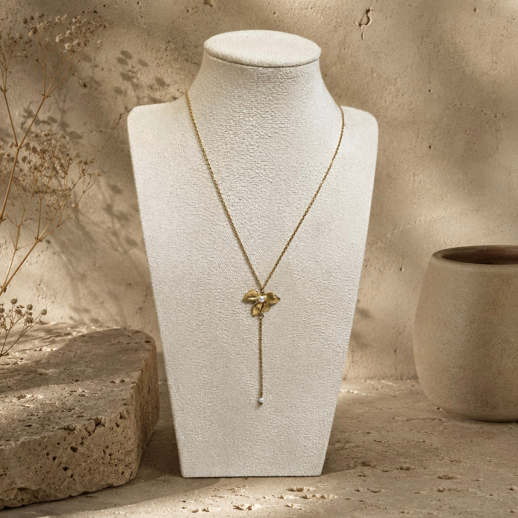 Collier doré avec pendentif fleur et perle blanche présenté sur buste