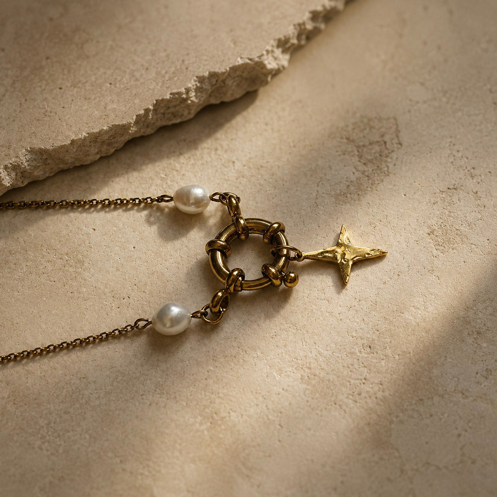 Détail d’un collier doré avec fermoir rond, pendentif étoile et perles blanches