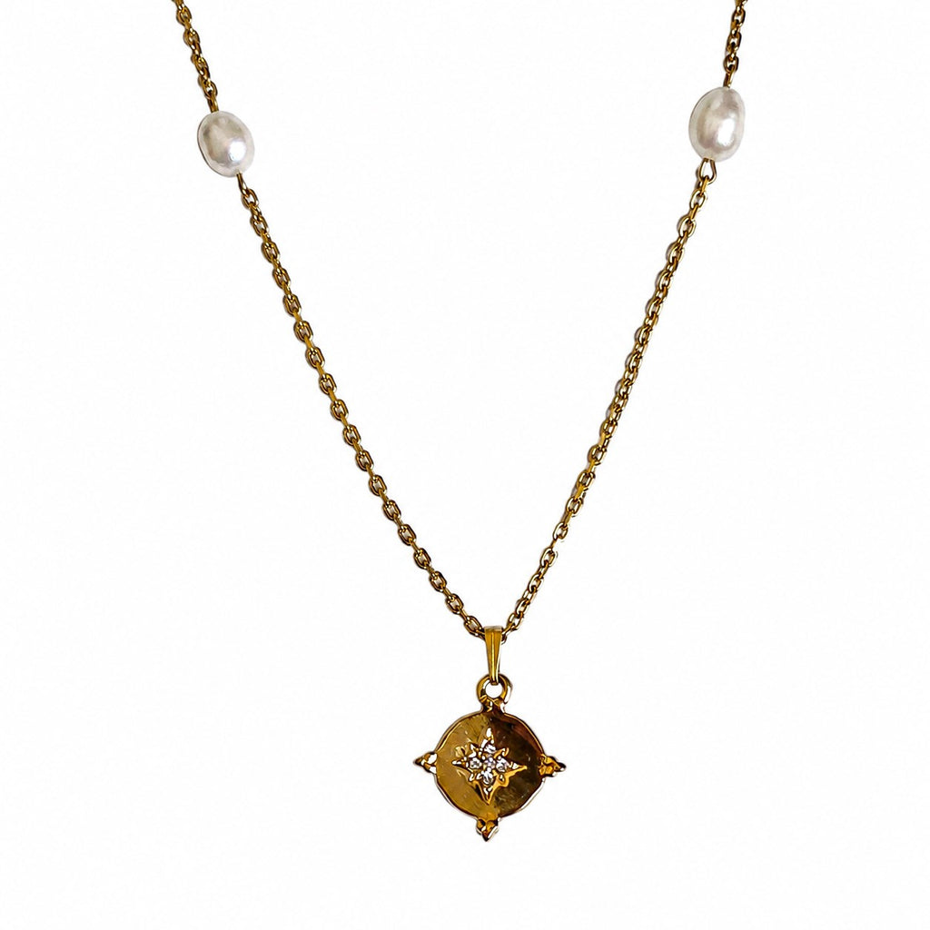 Collier doré avec pendentif étoile serti et perles blanches sur fond blanc