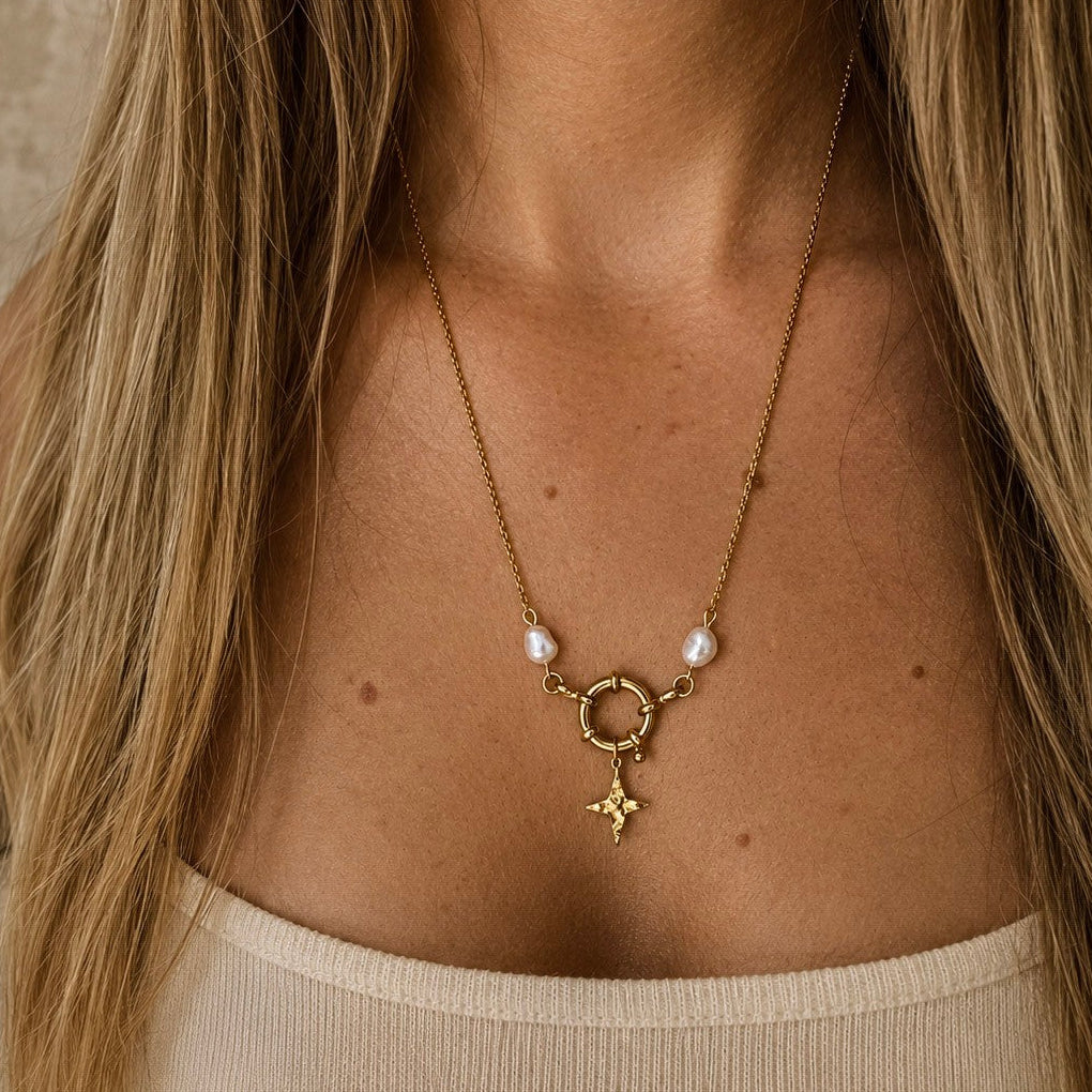 Collier doré porté avec pendentif étoile, fermoir rond et perles blanches