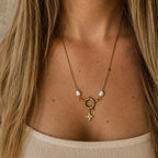 Collier doré porté avec pendentif étoile, fermoir rond et perles blanches