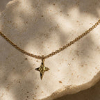 Gros plan sur un collier doré à pendentif étoile martelé posé sur une pierre claire.