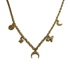 Détail d’un collier fin doré à breloques avec lune, œil, étoile, libellule et demi-corne