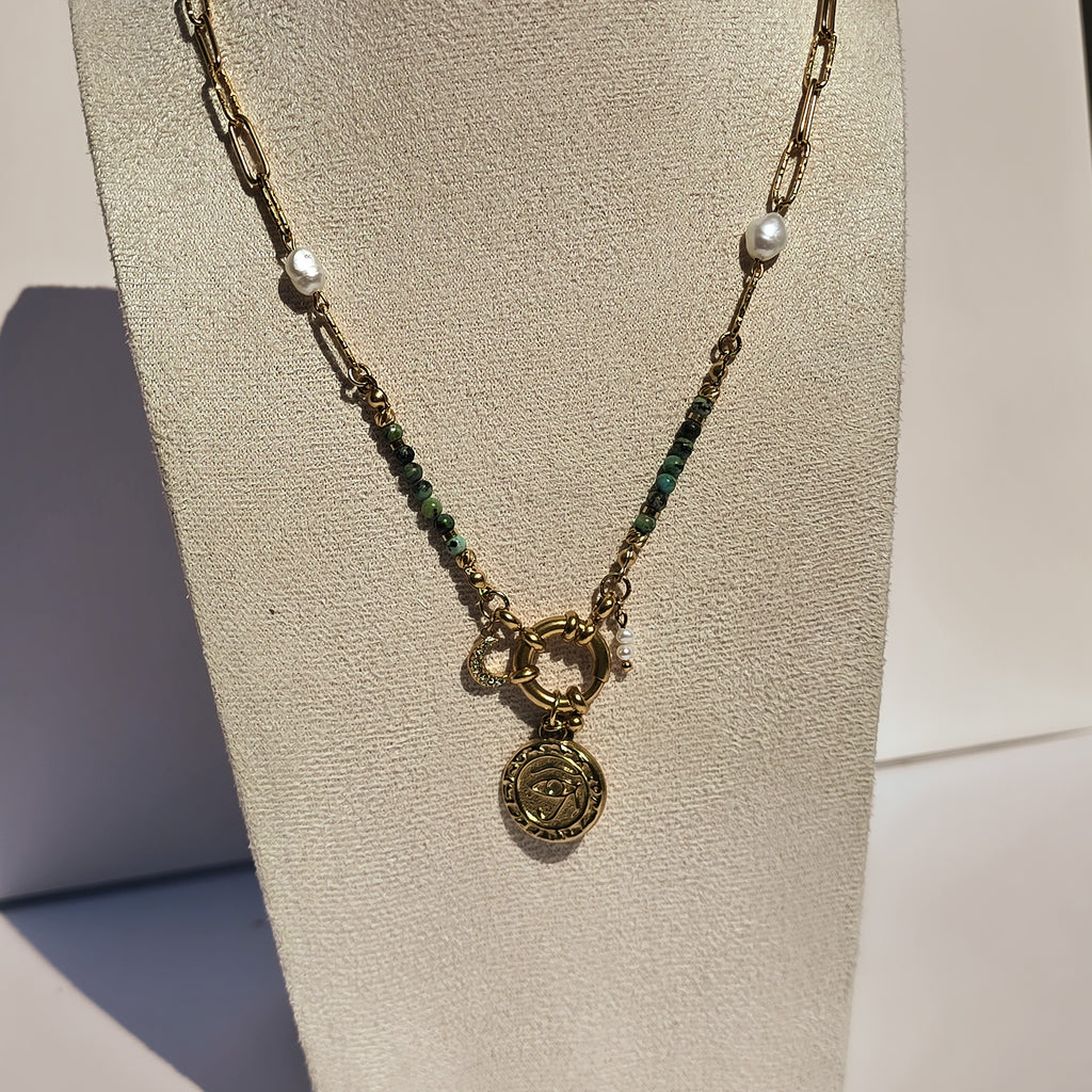 Collier doré avec jaspe vert, perles blanches et pendentif œil présenté sur buste