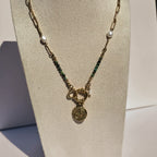 Collier doré avec jaspe vert, perles blanches et pendentif œil présenté sur buste