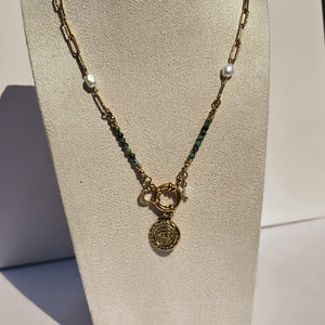 Collier doré avec jaspe vert, perles blanches et pendentif œil présenté sur buste