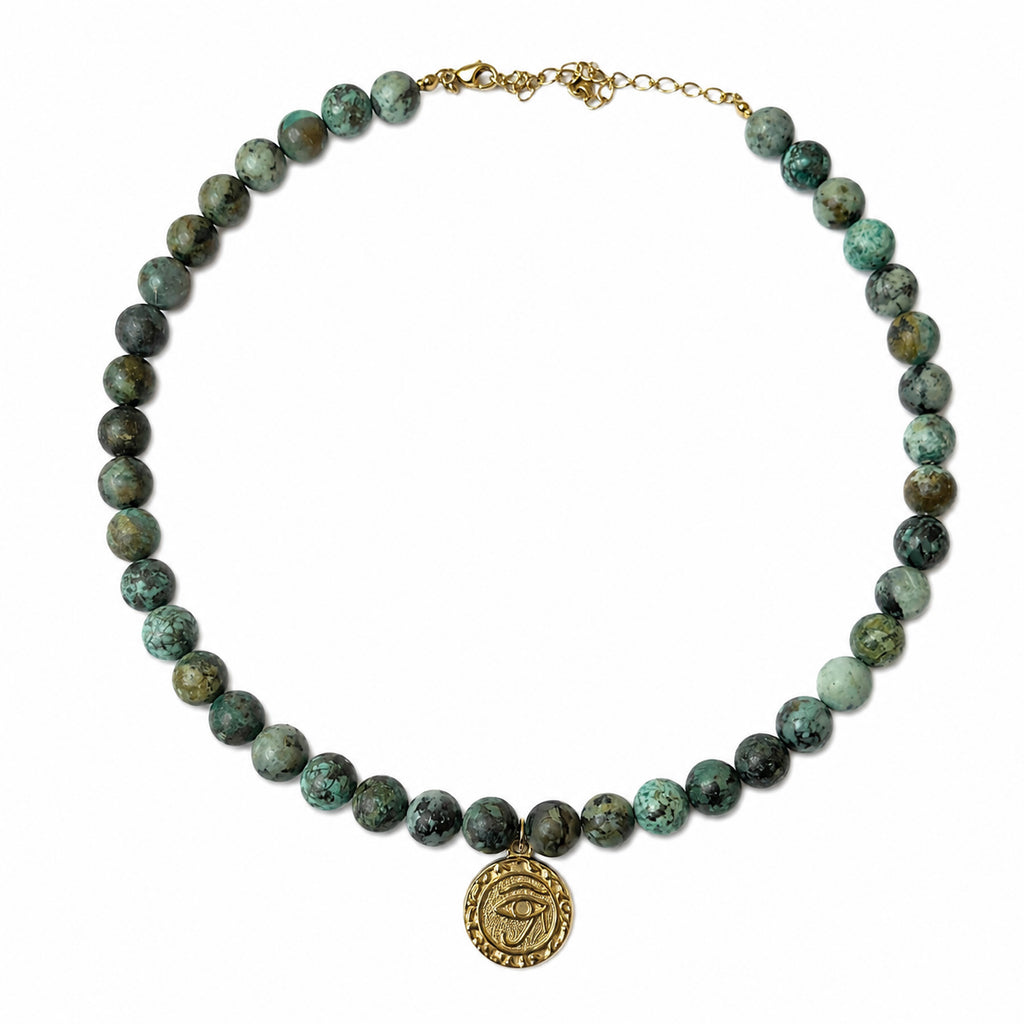 Collier en jaspe turquoise africain avec médaille œil dorée porté sur fond blanc