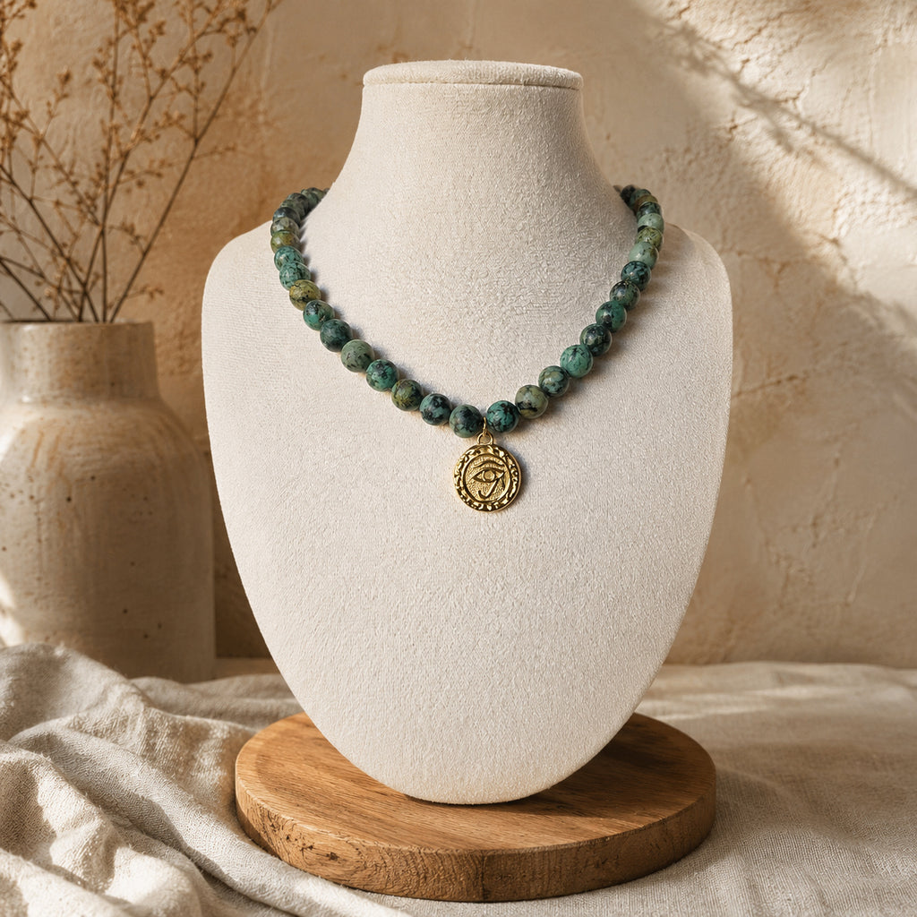 Collier en jaspe turquoise africain avec médaille œil dorée porté sur buste