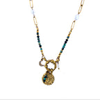 Collier doré avec jaspe vert, perles blanches et pendentif œil sur fond clair