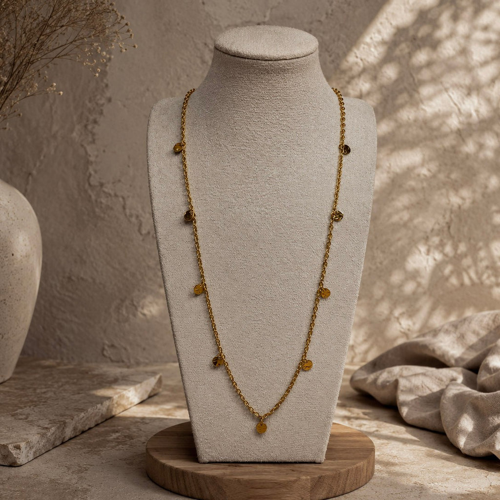 Collier long doré à petites pampilles rondes présenté sur un buste