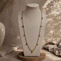 Collier long doré à petites pampilles rondes présenté sur un buste