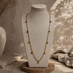 Collier long doré à petites pampilles rondes présenté sur un buste