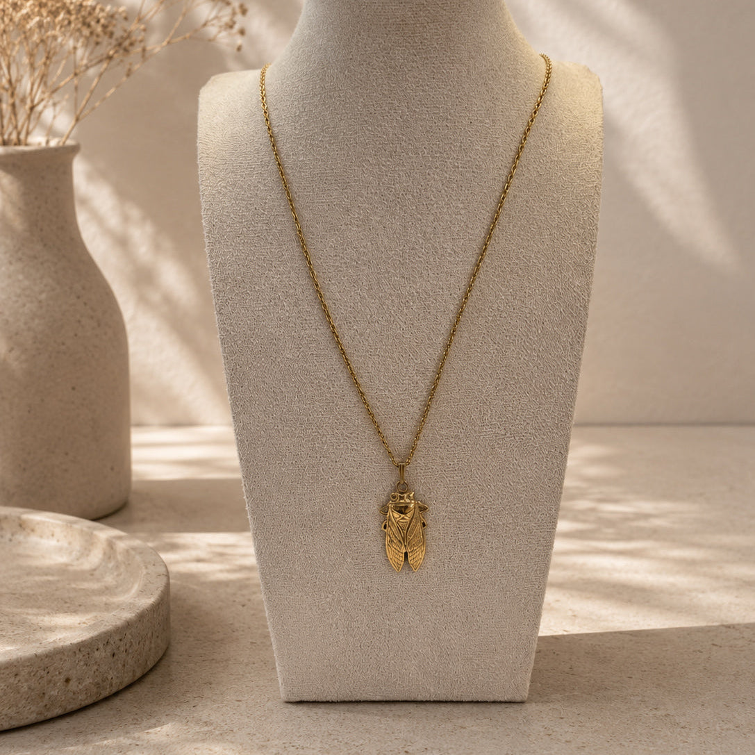 Collier long doré avec pendentif cigale sur buste beige, bijou inspiré de la Provence