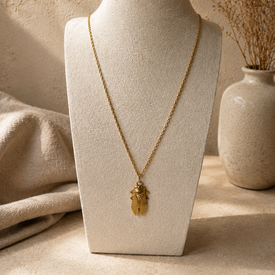 Collier long doré avec pendentif cigale sur buste beige, bijou inspiré de la Provence