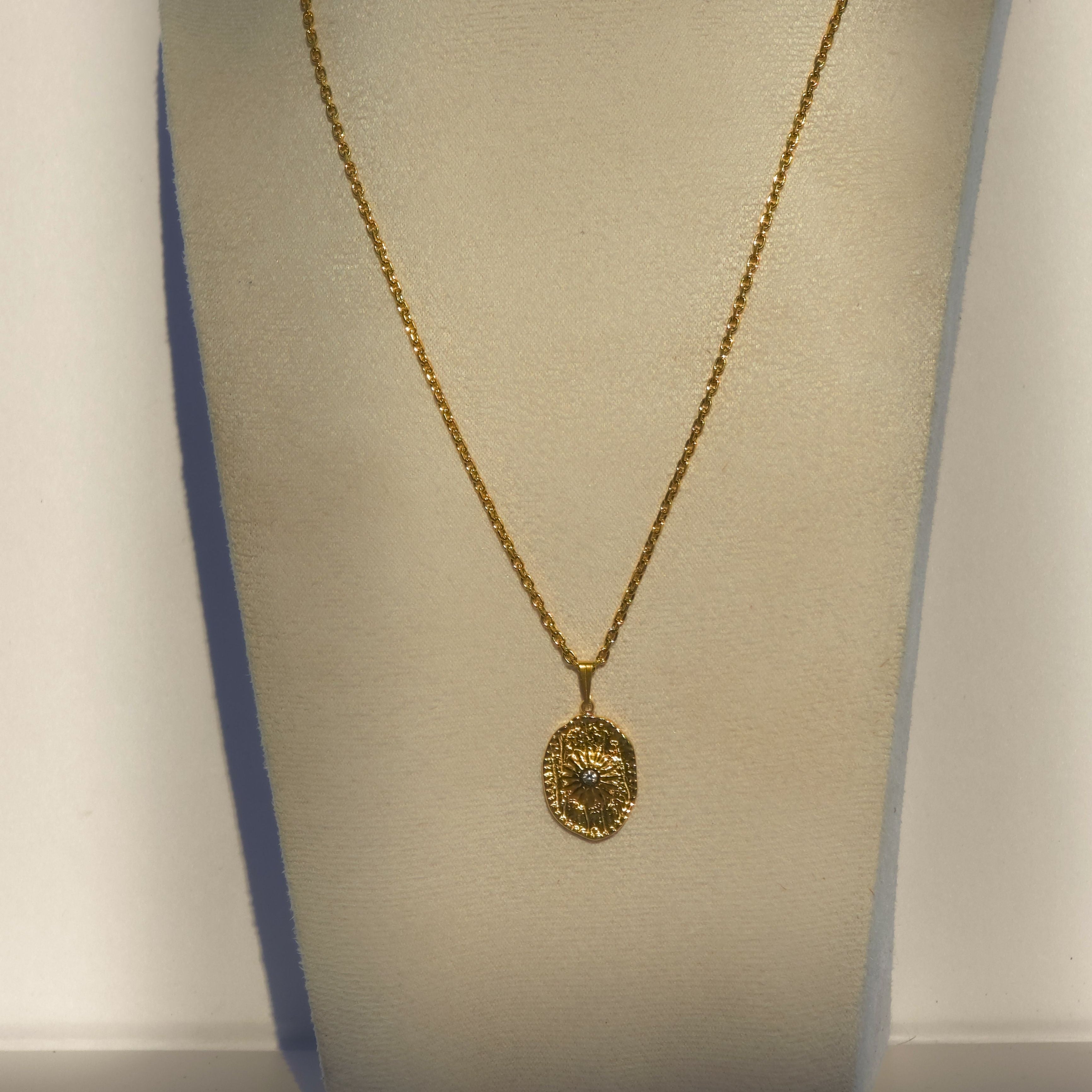Collier long doré avec pendentif ovale soleil et oxyde de zirconium présenté sur buste