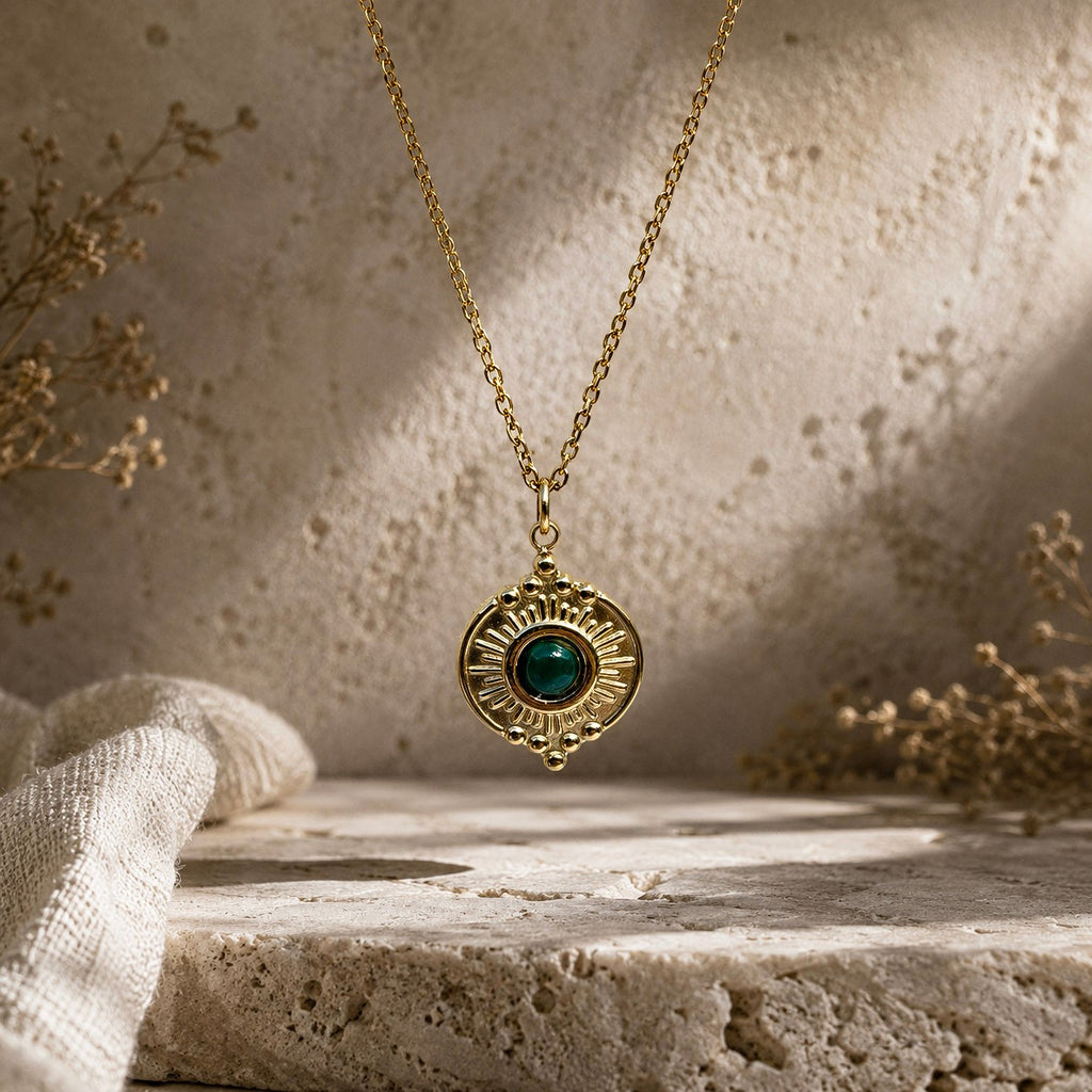 Détail d’un pendentif soleil doré avec pierre verte type malachite