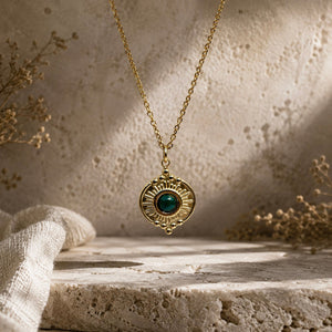 Détail d’un pendentif soleil doré avec pierre verte type malachite